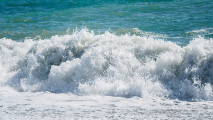 Waves and splashes of water against the sea on a sunny summer day