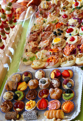 buffet with trays filled with sweet pastries and sandwiches