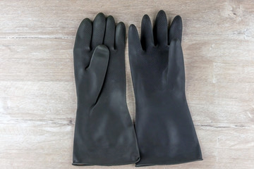 black protective rubber gloves for working with caustic substances, on a light wooden background, short focus