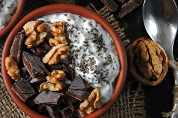 Two cups with yogurt with chia seeds, walnuts and dark chocolate. Breakfast or dessert for two. Healthy food. Keto diet. Diet recipes ideas. Shabby style. Dark background.