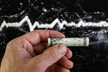 a clinical picture of a drug overdose: a folded bill for cocaine use next to a blurred cardiogram outline