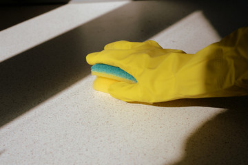 Hand in yellow rubber glove washing surface on a sunny day. Spring cleaning.brown color toned