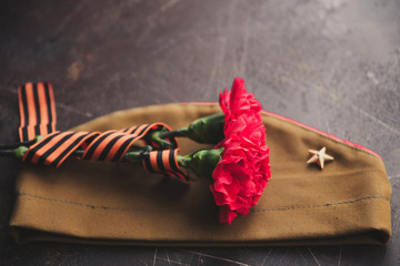 background for postcards by may 9, victory day: cap, letters, carnations and St. George ribbon