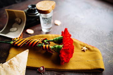 background for postcards by may 9, victory day: cap, letters, carnations and St. George ribbon