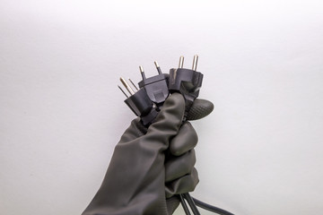 Fototapeta na wymiar concept of energy dependence: several different plugs and cables in the person's hand, black protective glove