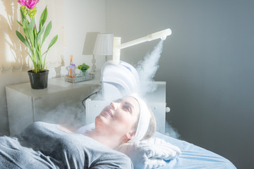 Beauty treatment of face with ozone facial steamer in beauty center. Beaultiful Blonde Girl.