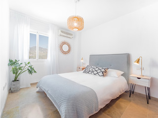 Comfortable hotel bedroom with felt headboard with natural fabric cushion, rattan lamp, wood...
