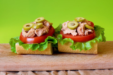 Tuna sandwich on wooden tray. Green background.