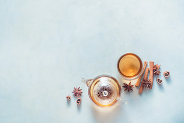 Obraz na płótnie Canvas Glass teapot and tea bowls on a white wooden background with cinnamon and anise stars. Minimalist food flat lay with spices.