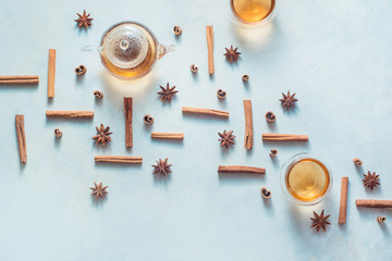 Cinnamon and anise pattern with teapot and tea bowls on a white wooden background with copy space. Hot drink creative flat lay.