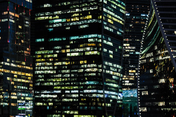 Fototapeta na wymiar Glass modern business skyscraper at night. The windows of the night glowing business center.