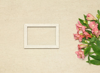 Flat lay frame with pink flowers on beige granite background