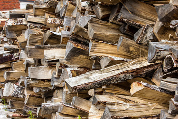 A wall of logs stacked on top of each other, a full yard with a pile of firewood, wooden beams. Wooden natural texture.  Island Suomenlinna in Helsinki, Finland.