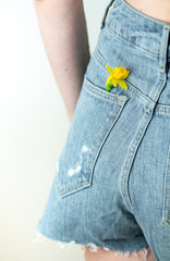 Spring background with copy space, easter daffodils in the pocket of the beautiful girl's shorts