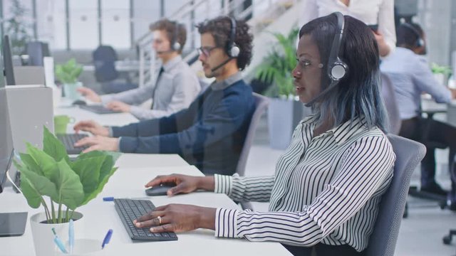 Team of Handsome and Beautiful Diverse Multicultural Customer Service Operators Working at a Busy Modern Call Center with Specialists Wearing Headsets and Actively Taking Calls. 