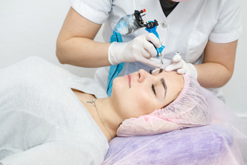Obraz na płótnie Canvas Permanent makeup, tattooing of eyebrows. Cosmetologist applying make up