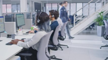 Team of Handsome and Beautiful Diverse Multicultural Customer Service Operators Working at a Busy Modern Call Center with Specialists Wearing Headsets and Actively Taking Calls.  - Powered by Adobe