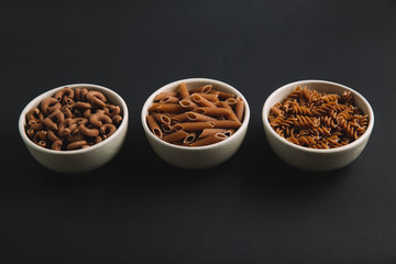 Variety of whole grain pasta, horizontal, dark background, free space for text
