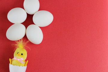 White chicken eggs and yellow toy chicken on red background. happy Easter. Symbol of new life. empty space for text