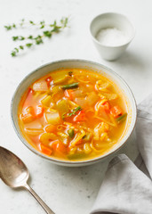 Spring vegetable soup with chicken stock for one person on white table.