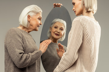 Joyful positive woman waving to her reflection