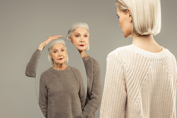 Nice aged woman holding an oval mirror