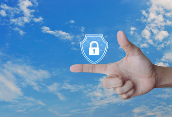 Hand pressing padlock with shield flat icon over blue sky with white clouds, Business security insurance concept
