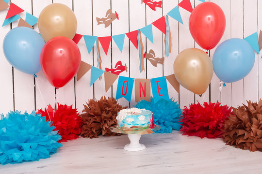 Photo Zone With Paper Garlands, Balloons, Paper Balls, Pom Poms, Confetti And Cream Cake. Birthday Cake. Smash Cake. One Year. Blue, Gold, Beige, Brown Colors. Pilot, Sky