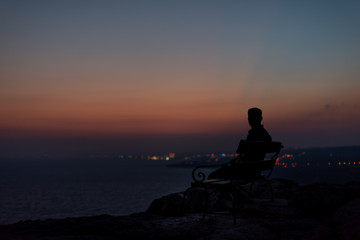 Silhouette of man meditating on the beach at sunset. Sea view from the mountain.