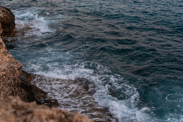 Waves crashing on rocks. Sea foam.  Green waves after sunset. 