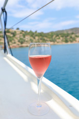 A glass of rose wine on the deck for the beginning of a summer holiday on a yacht in the Aegean Sea.