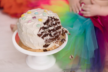 Photo zone with paper garlands, balloons, paper balls, pom poms, confetti and cream cake. Birthday cake. Smash cake. One year. Pink, white, blue, green, red,yellow colors