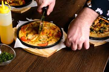father cuts homemade pizza for a child into pieces