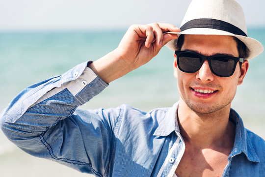 Portrait of smiling handsome man relax in sunglasses and straw hat on the tropical beach.Summer vacations