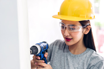 Young woman construction worker working with screwdriver to drill in a house entrance