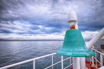 big green ship bell and cloudy sky