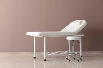 Treatment couch with stool near color wall