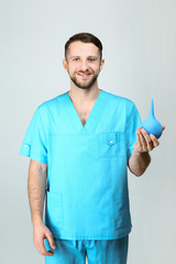 Male nurse with medical pear on light background