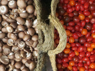 two baskets filled with little tomatoes and mushrooms