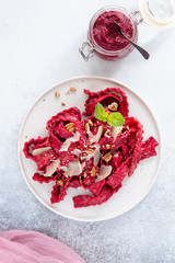 Top view of vegetarian mafaldine pasta with beet pesto sauce, walnut and parmesan cheese on a white background