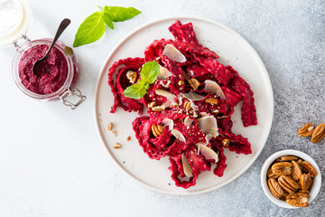 Top view of vegetarian mafaldine pasta with beet pesto sauce, walnut and parmesan cheese on a white background