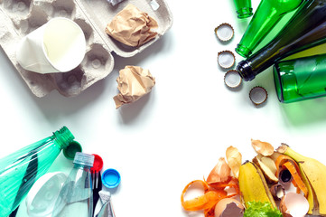 Sorted household garbage, top view close-up on white background. The concept of separate collection of household waste and environmental benefits. Paper, glass, plastic, food waste.