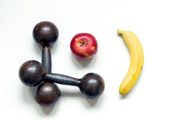 Two metal brutal dumbbells on a white background, top view close-up. Nearby lies an Apple and a banana, the concept of proper nutrition and a healthy lifestyle