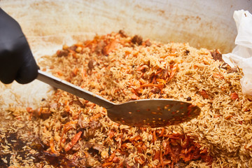 Asian traditional dish - pilaf. Cooking pilaf in a cauldron. Rice with meat and vegetables.