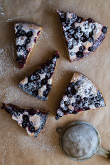 Homemade berry pie on baking paper. Slices of currant pie with icing sugar.  Top view