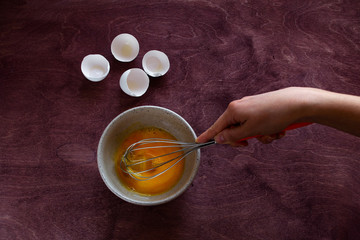 The process of making the cake, top view. Women's hands beating eggs for making dough
