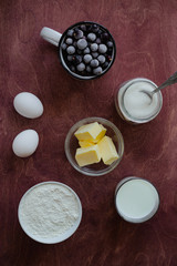 Ingredients for cooking berry pie. Eggs, sugar, milk, butter, flour, currants on a wooden table. Rustik style. Top view.