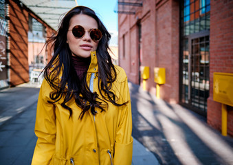 Fototapeta premium young woman in yellow raincoat at city street