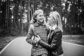 Fototapeta premium Family relationship concept. Woman during the city with the little adorable girl at street outdoors. Mother and daughter 