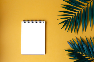 Notepad with palm leaves on an orange background.